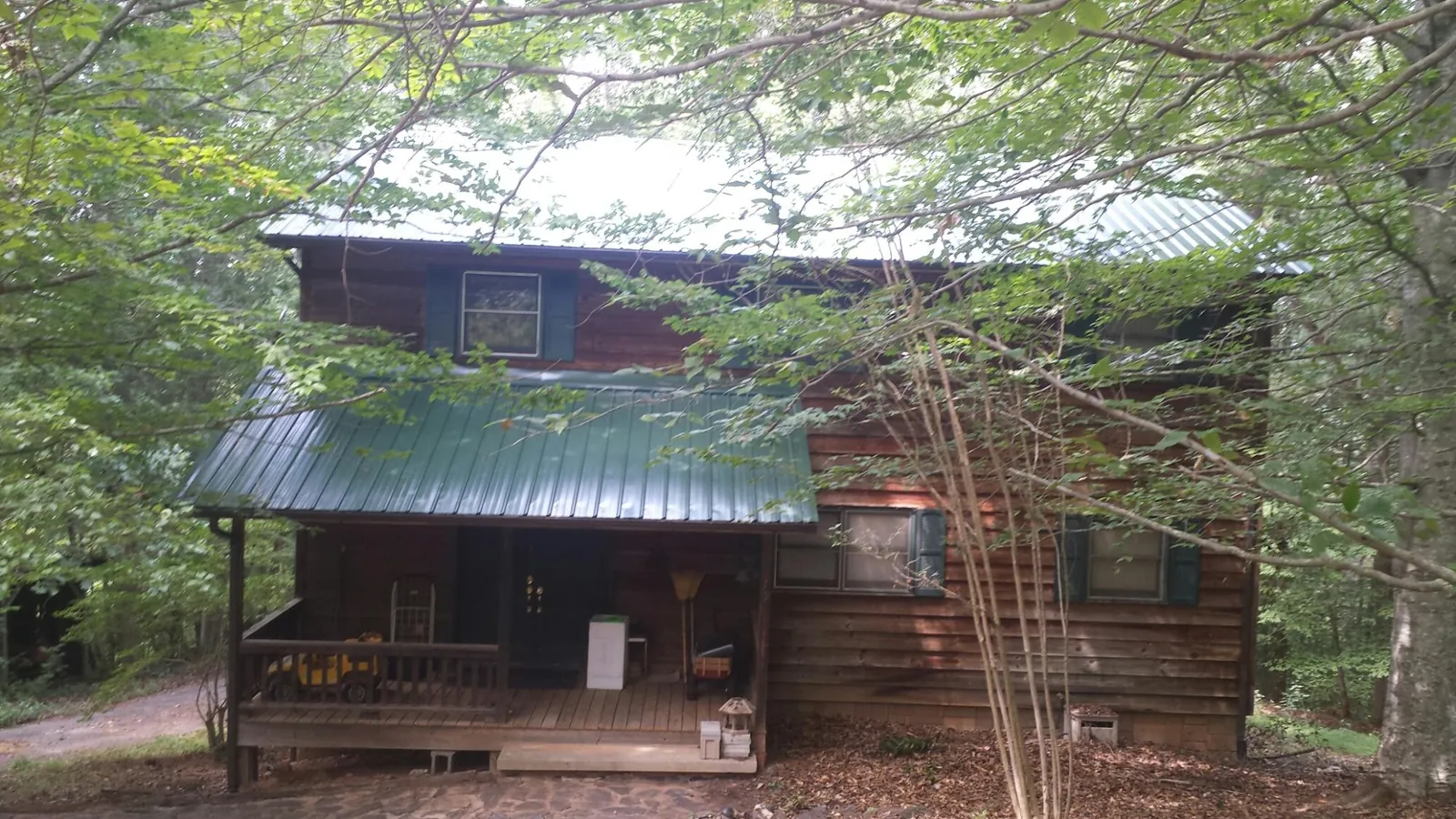Green metal roof and covered porch on a log cabin in Roxobel