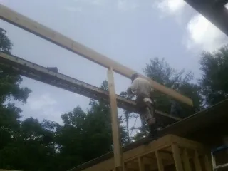 Carpenter setting a ridge beam over a new addition frame — Ice Dam Removal by Roofing Brothers in Roxobel