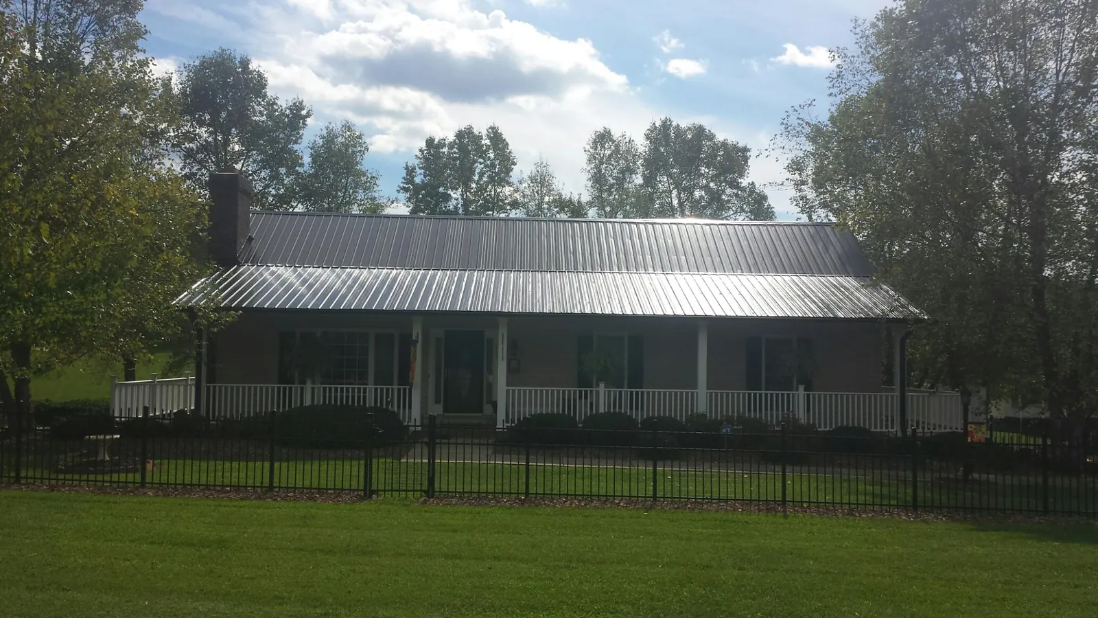 Gray metal roof on a brick ranch with a full width front porch — Gutter Guard Installation work by our crew in Roxobel