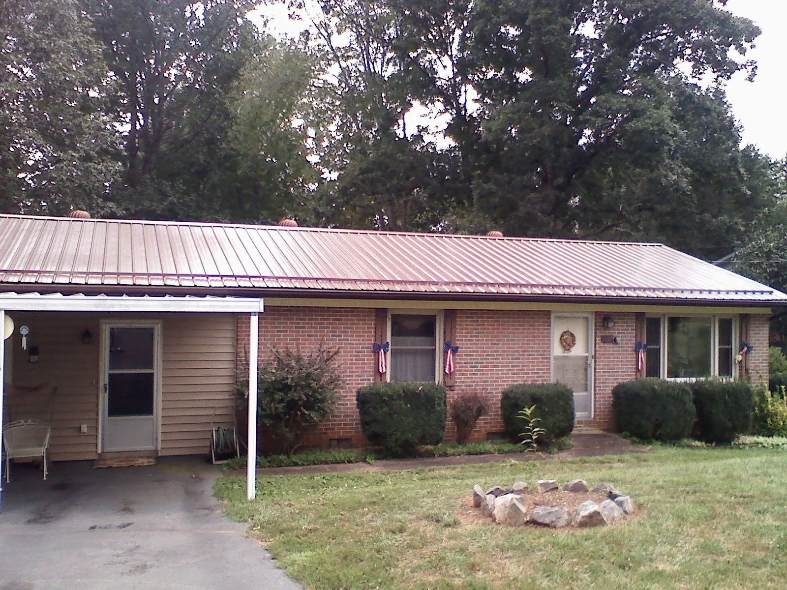 Bronze metal roof and carport on a brick ranch home — Roof Repair work by our crew in Roxobel