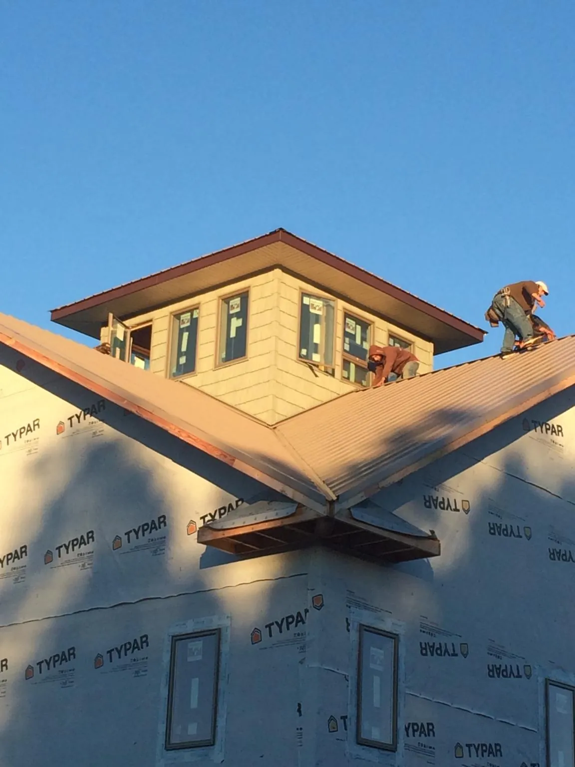 Roofers working around a rooftop cupola on a new metal roof at sunset — Roof Waterproofing in Roxobel by Roofing Brothers